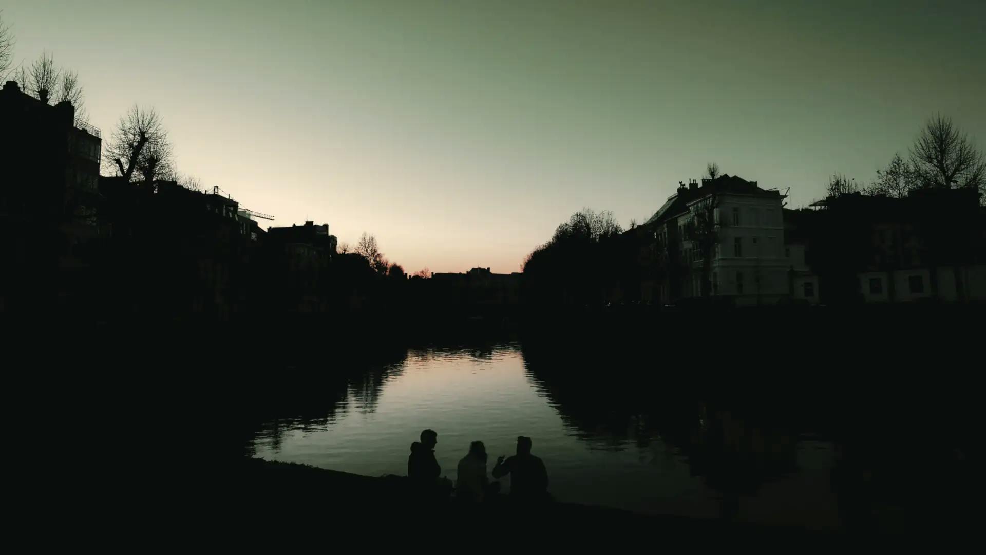 Trois amis profitant d'une escapade surprise personnalisée au coucher du soleil en Belgique avec Pop'in, découvrant des paysages uniques et des expériences mémorables.