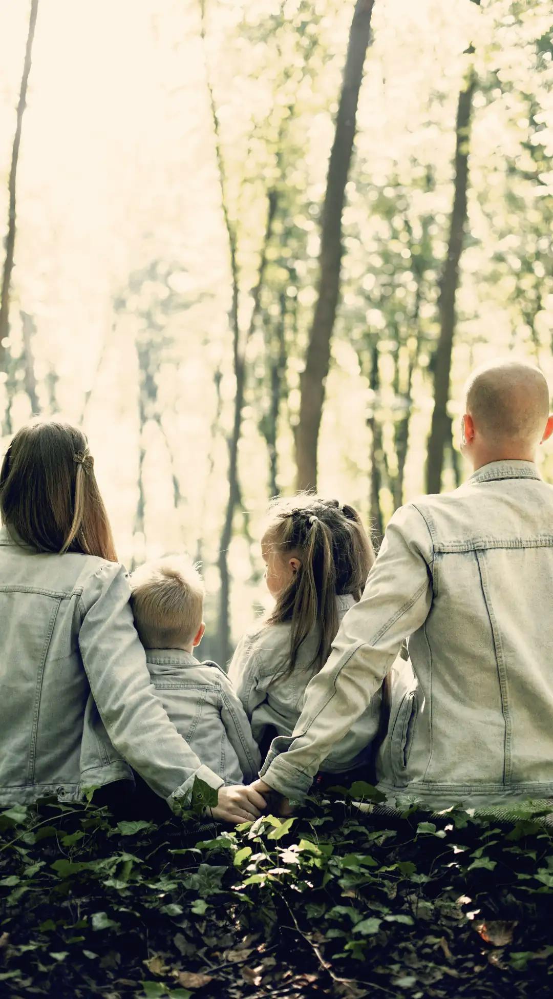 Famille se tenant par la main dans une forêt, évoquant la cohésion et les découvertes naturelles lors des escapades familiales avec Pop'in.